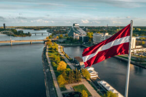 Aerial panorama of Riga city with a big Latvian flag in the foreground. Golden hour.